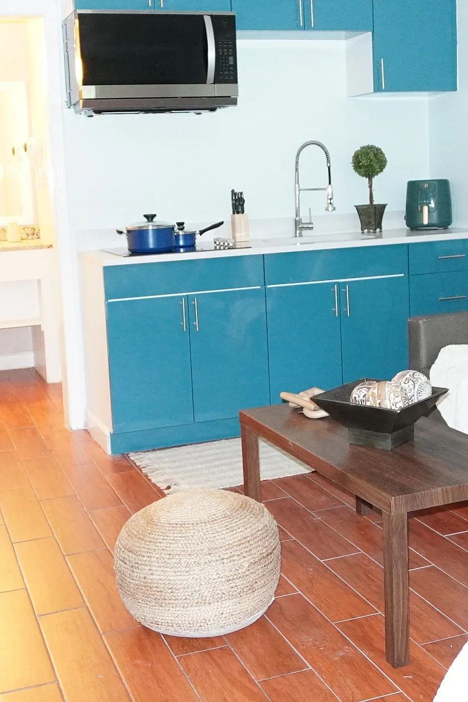 Charming studio apartment featuring elegant blue cabinets, cozy living area with plush sofa, and inviting dining nook. Perfect blend of style and comfort.