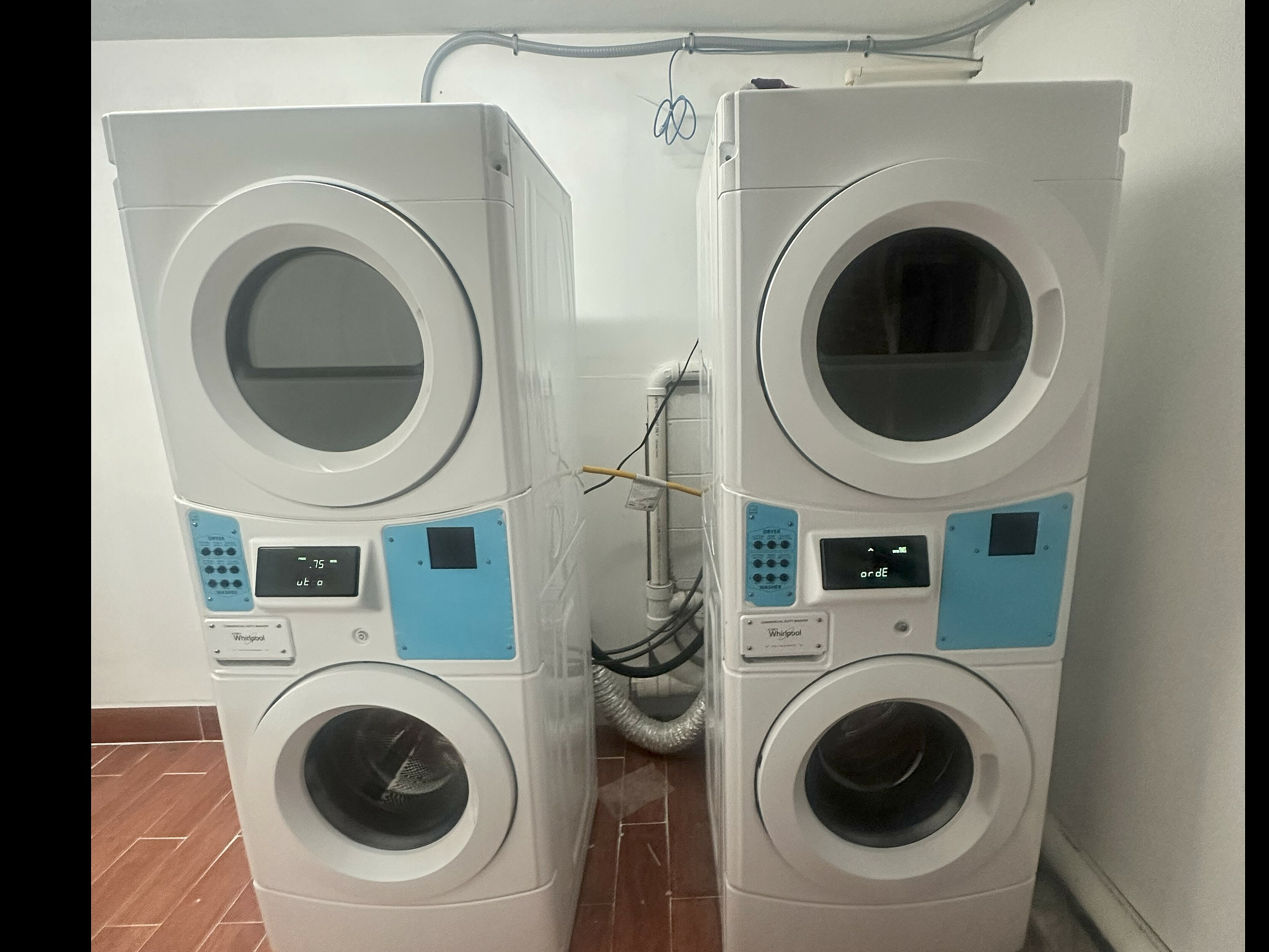 Modern laundry room featuring sleek stacked washing and drying machines with digital interfaces, set against a chic tiled floor.