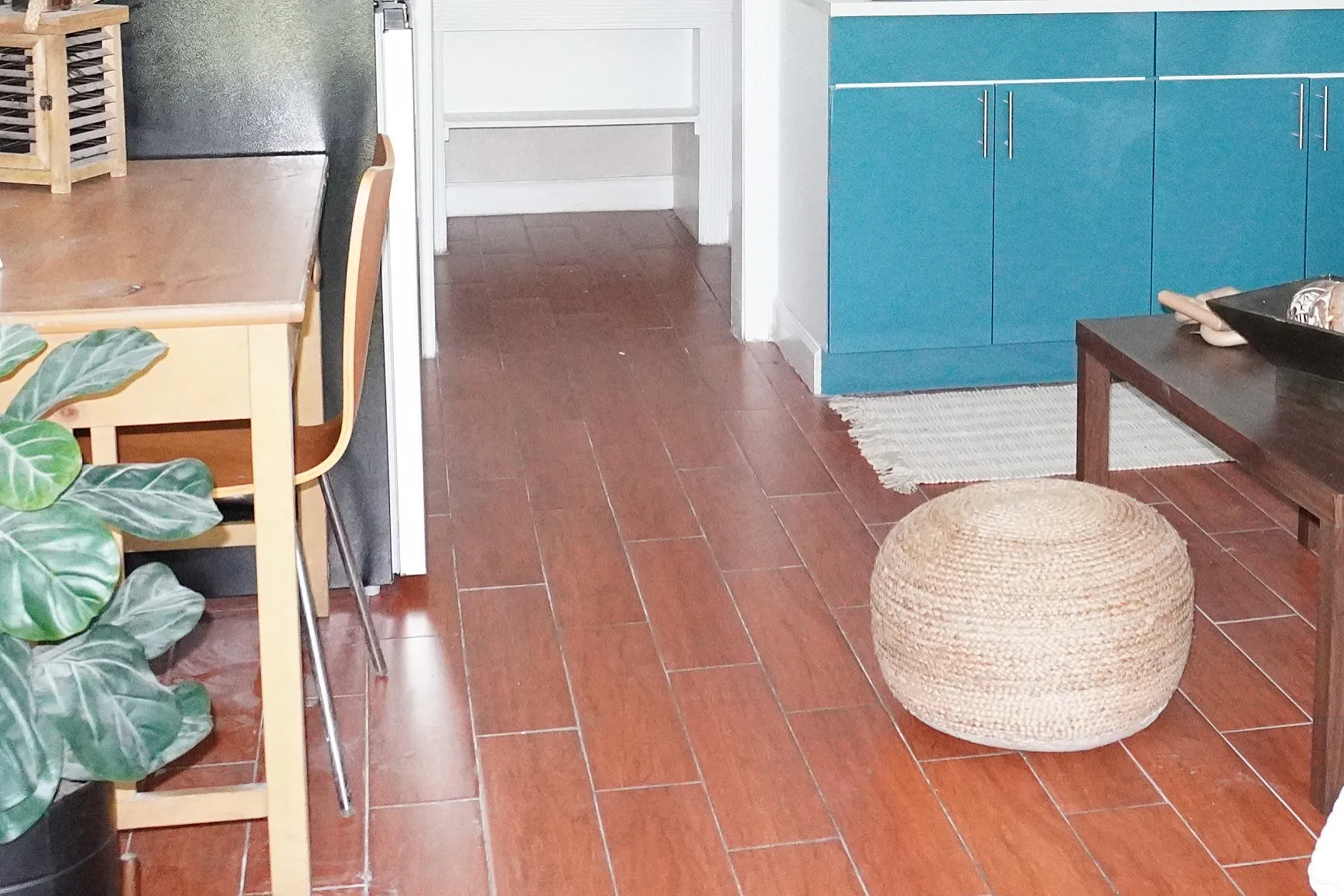 Charming apartment interior with vibrant teal kitchen cabinets, cozy living area, and stylish decor. Perfectly combines modern elegance with comfort, featuring a sleek workspace, plush sofa, and inviting ambiance.