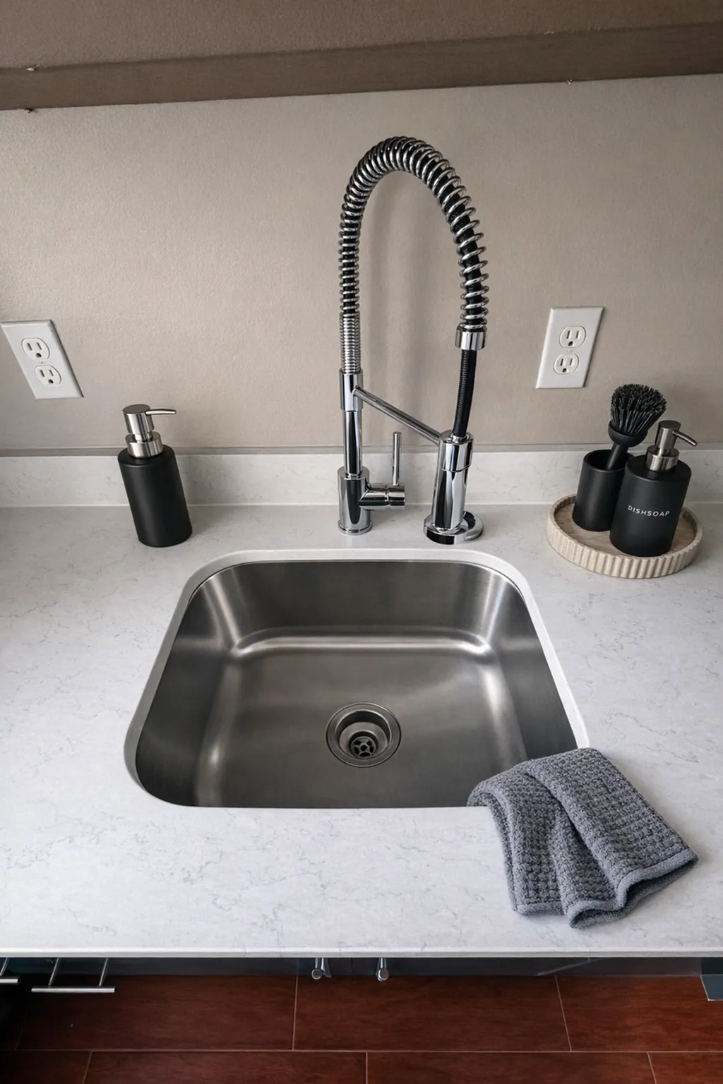 Sleek modern kitchen sink with a high-arc faucet, set in a stylish countertop, complemented by chic soap and brush holders.