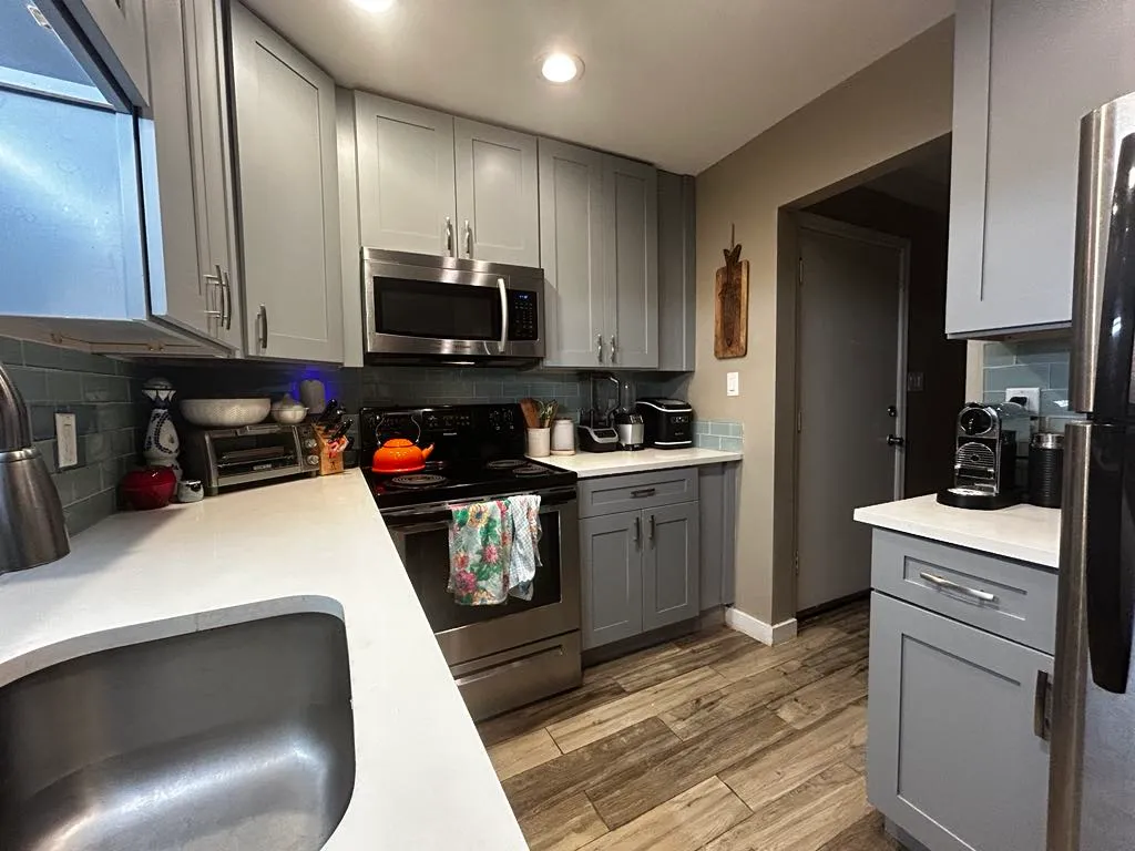 Modern kitchen featuring sleek grey cabinets, stainless steel appliances, and stylish subway tile backsplash.
