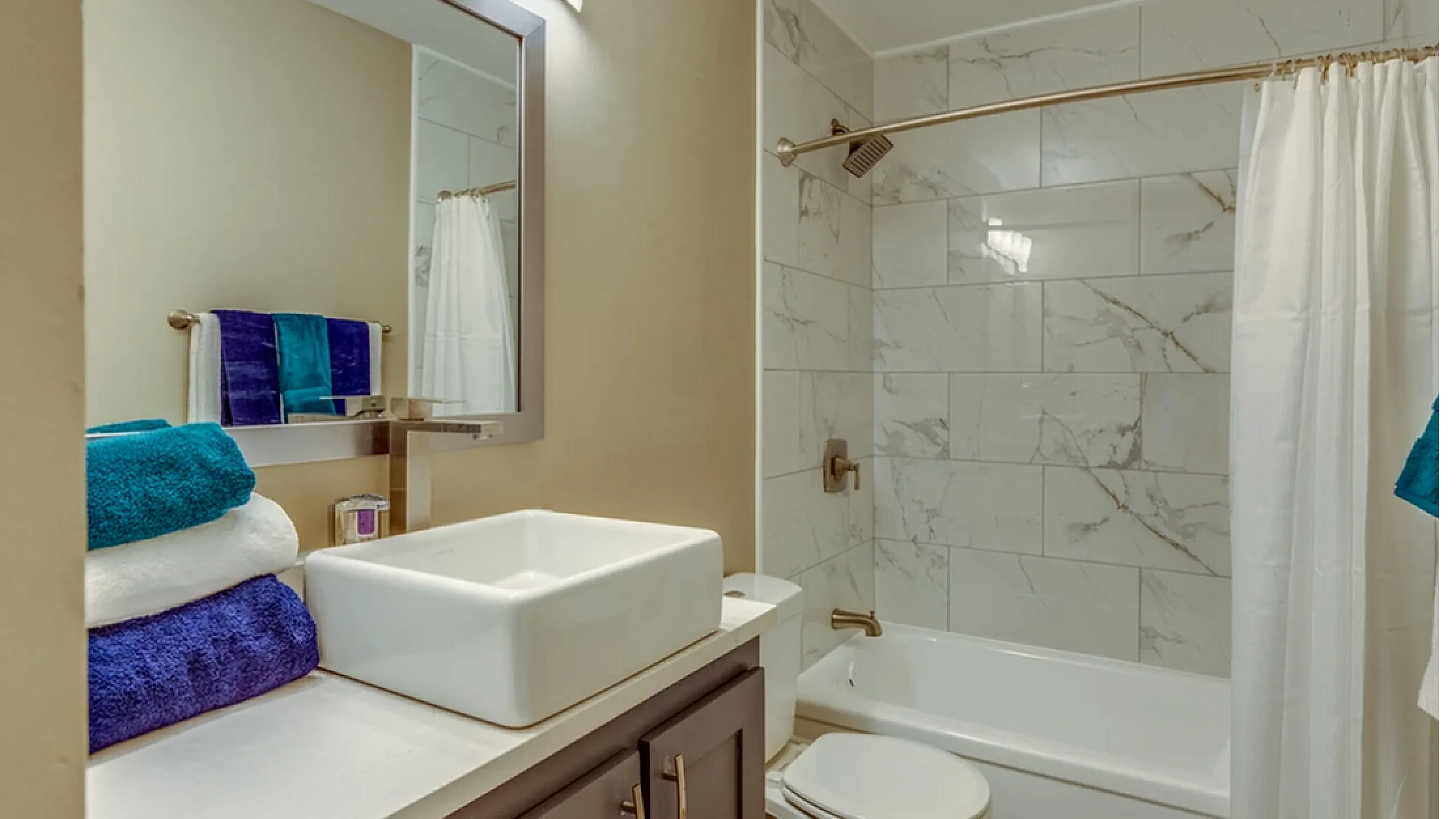 Elegant bathroom featuring a modern vanity, vessel sink, and marble-tiled shower area with chrome fixtures.