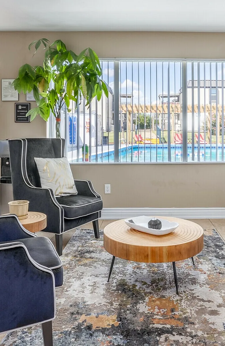 Bright and modern living area with stylish velvet chairs, a designer rug, and a view of the inviting pool outside.