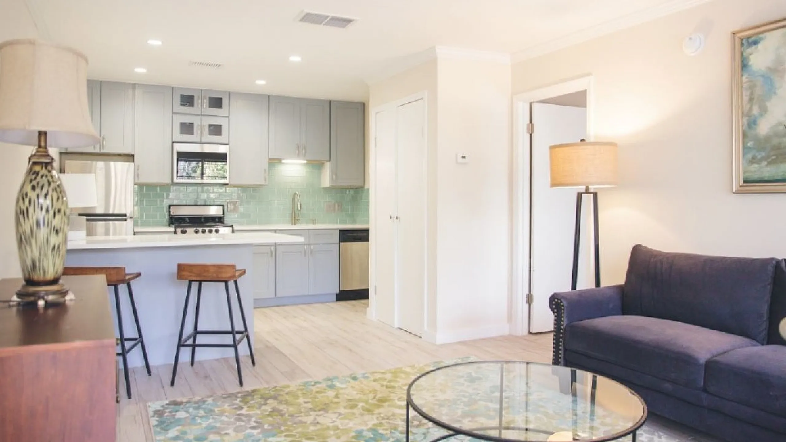 Bright and modern open-concept living room with elegant kitchen featuring sleek cabinetry, chic island with stools, and cozy seating area.