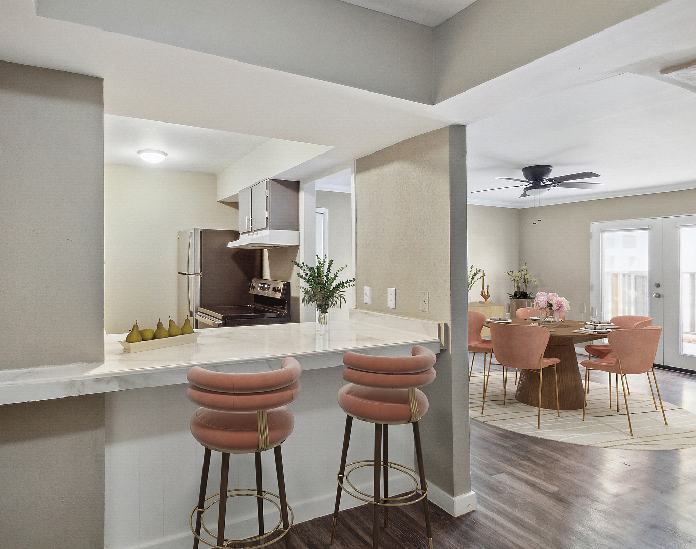 Modern kitchen featuring sleek marble countertops and stylish bar seating, seamlessly leading into an elegant dining area with sophisticated furnishings and natural lighting.