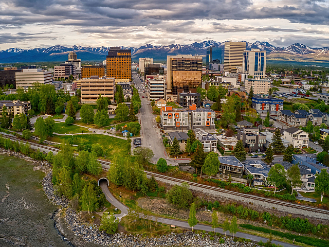 Vibrant urban cityscape with diverse architecture and lush greenery set against stunning mountain vistas.