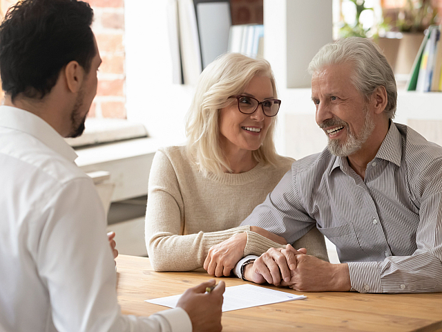 Happy couple discussing apartment options with a real estate agent, showcasing a welcoming and customer-focused experience.