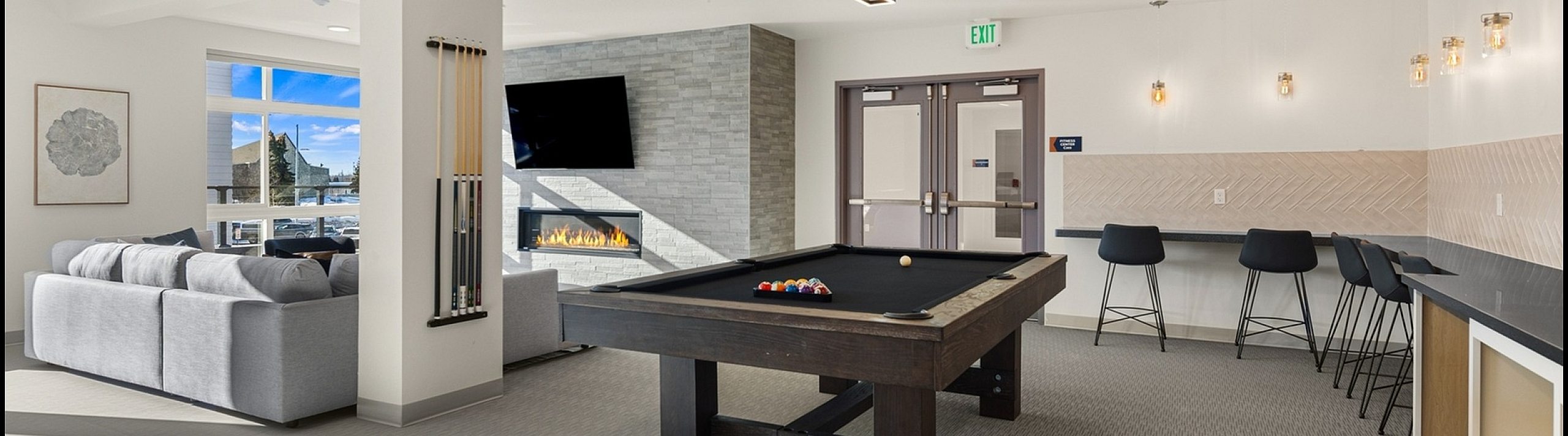 Elegant recreation lounge with a billiards table, modern seating area, and a warm fireplace.