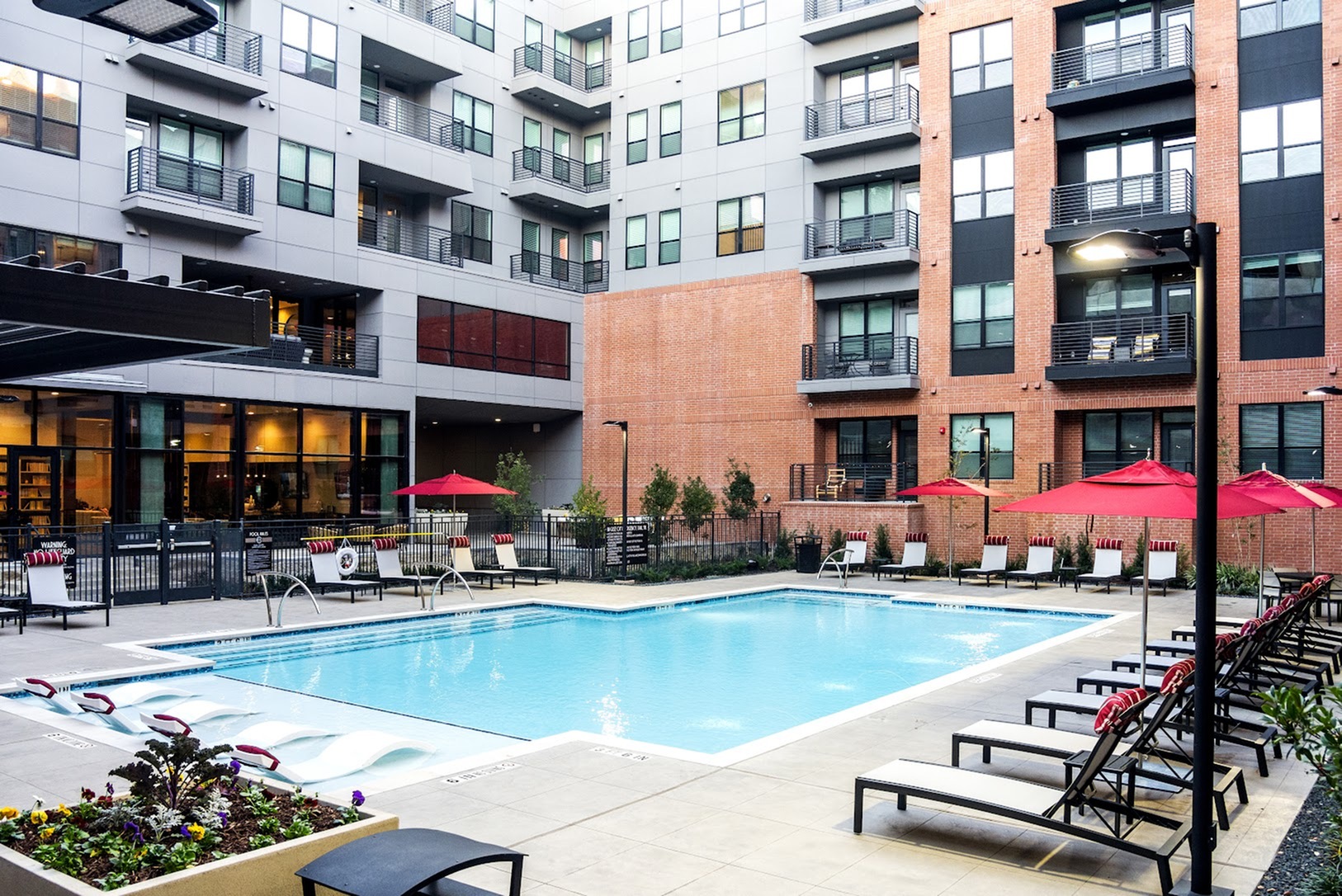 Inviting outdoor pool area with loungers and umbrellas, surrounded by modern apartment buildings.