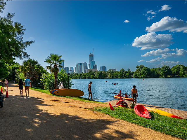Scenic riverside walkway bordered by lush trees and vibrant greenery, perfect for a peaceful stroll or dog walk.