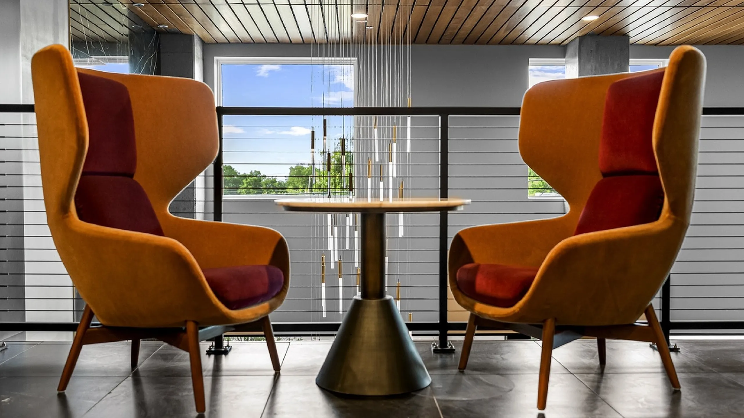 Contemporary lounge area with two chic orange armchairs and a modern round table, offering a stylish setting for relaxation.