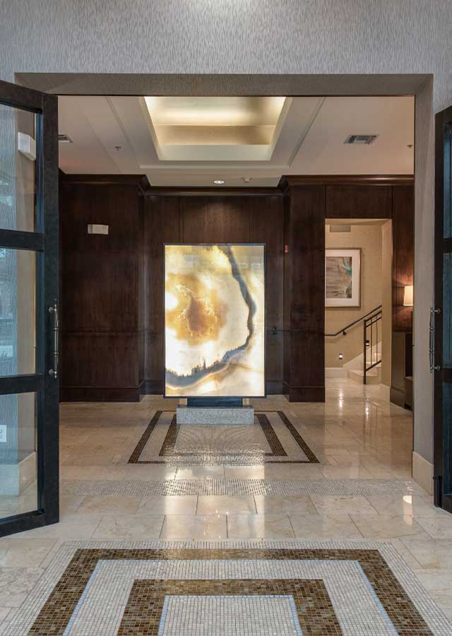 Elegant lobby entrance with artistic backlit panel, polished marble flooring, and modern architectural details.
