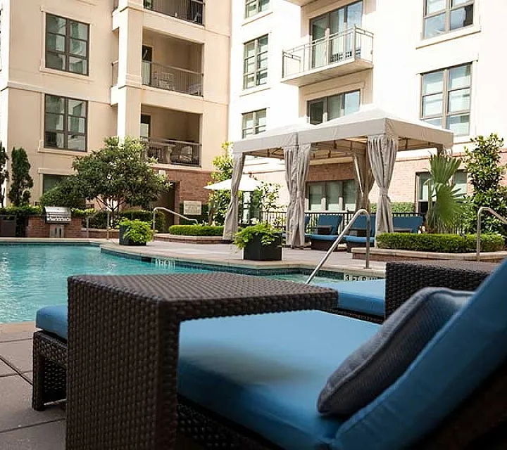 Luxurious pool area featuring a serene swimming pool, elegant cabana, and stylish lounging area surrounded by lush greenery.