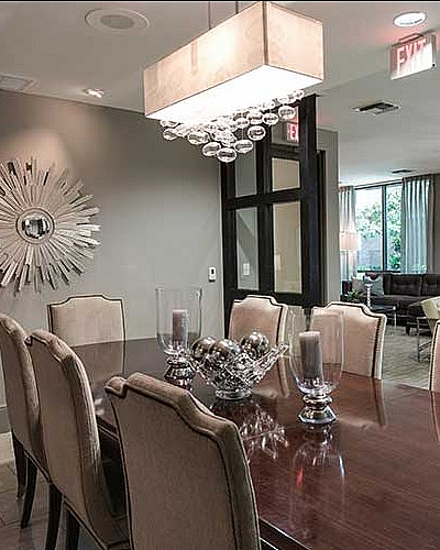 Elegant dining area with modern chandelier, stylish decor, and view into a seating area.