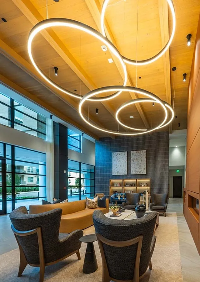 Sophisticated lounge area with modern circular chandeliers, elegant seating, and tall windows, offering a luxurious living experience.