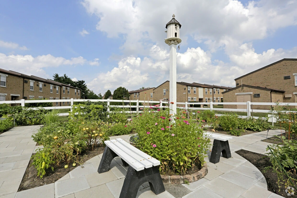 Willow Shores Palmyra Apartments community garden with flowers, benches and a bird feeder