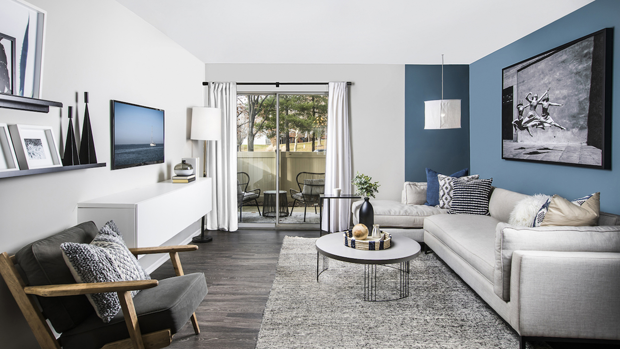 Spacious Living Room with Large Sliding Glass Doors Leading to Private Patio in an Autumn Town Center apartment.