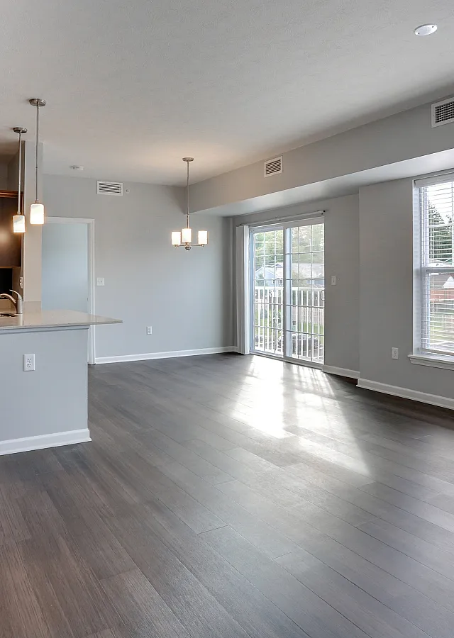 Bright open-concept living area with sleek hardwood floors, modern kitchen, and large windows offering scenic views.