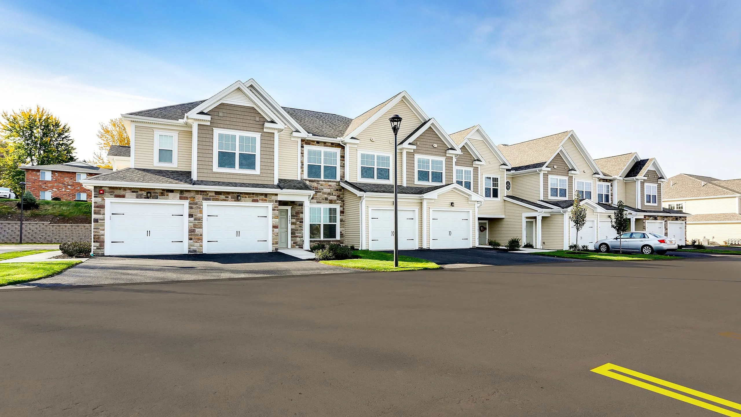 Modern townhouse exterior with attached garages, spacious driveways, and charming architecture in a serene suburban setting.
