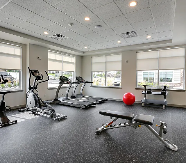 Bright and modern gym with state-of-the-art exercise equipment, featuring treadmills, an elliptical, and a spacious free weights area.