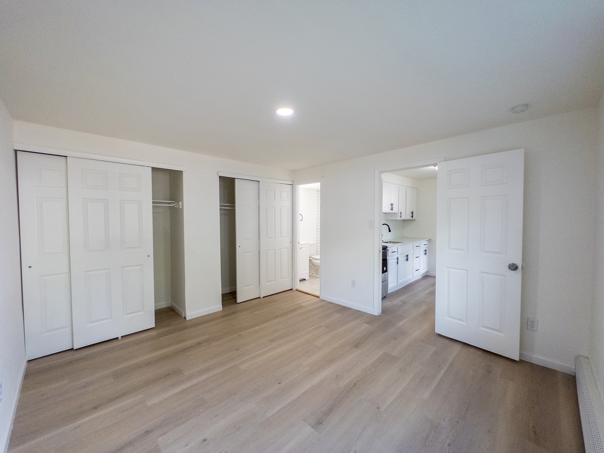 spacious bedroom with two closets, recessed lighting, doors leading to bathroom and kitchen