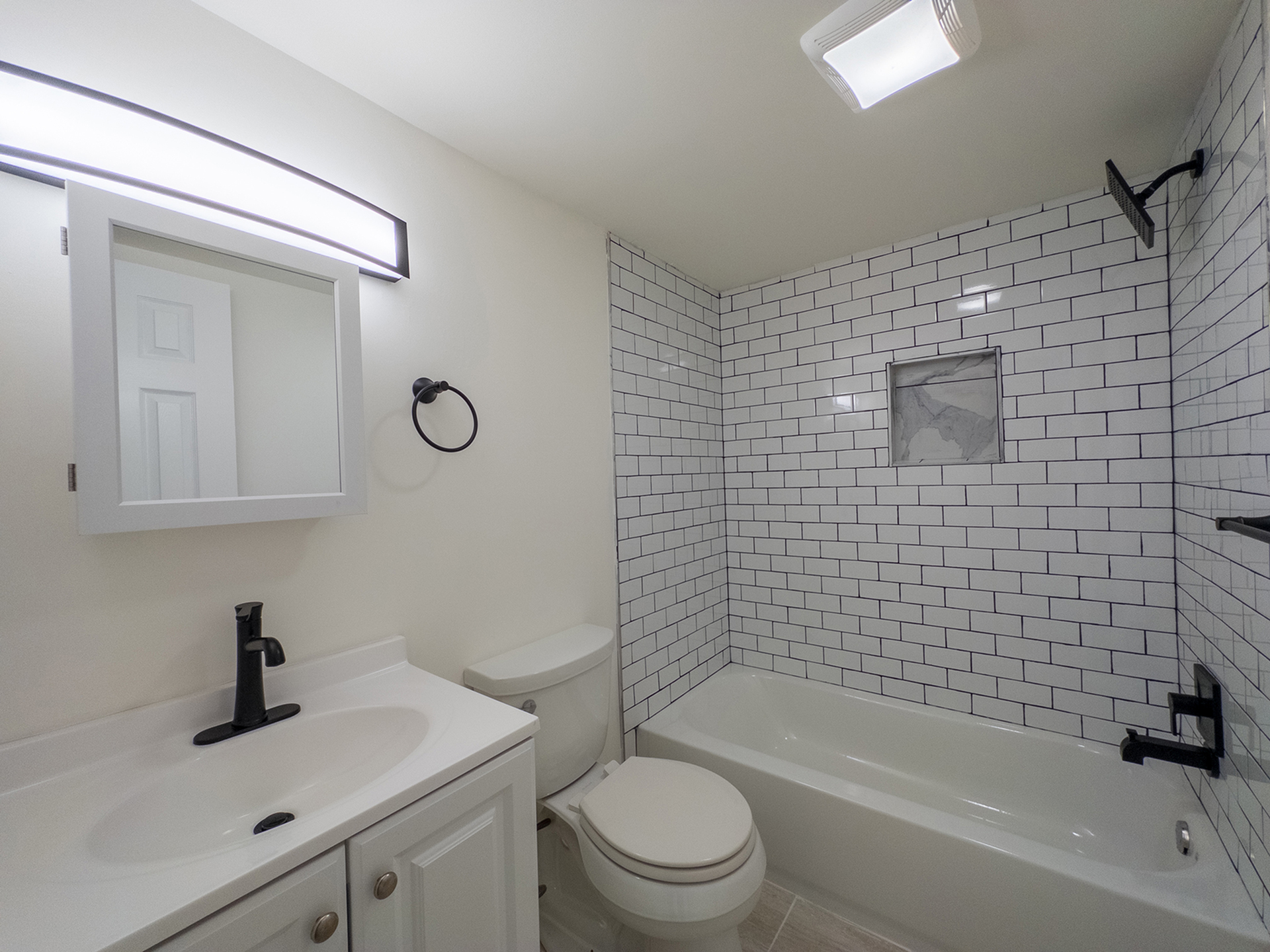 bright bathroom with tile surround shower, vanity sink with medicine cabinet
