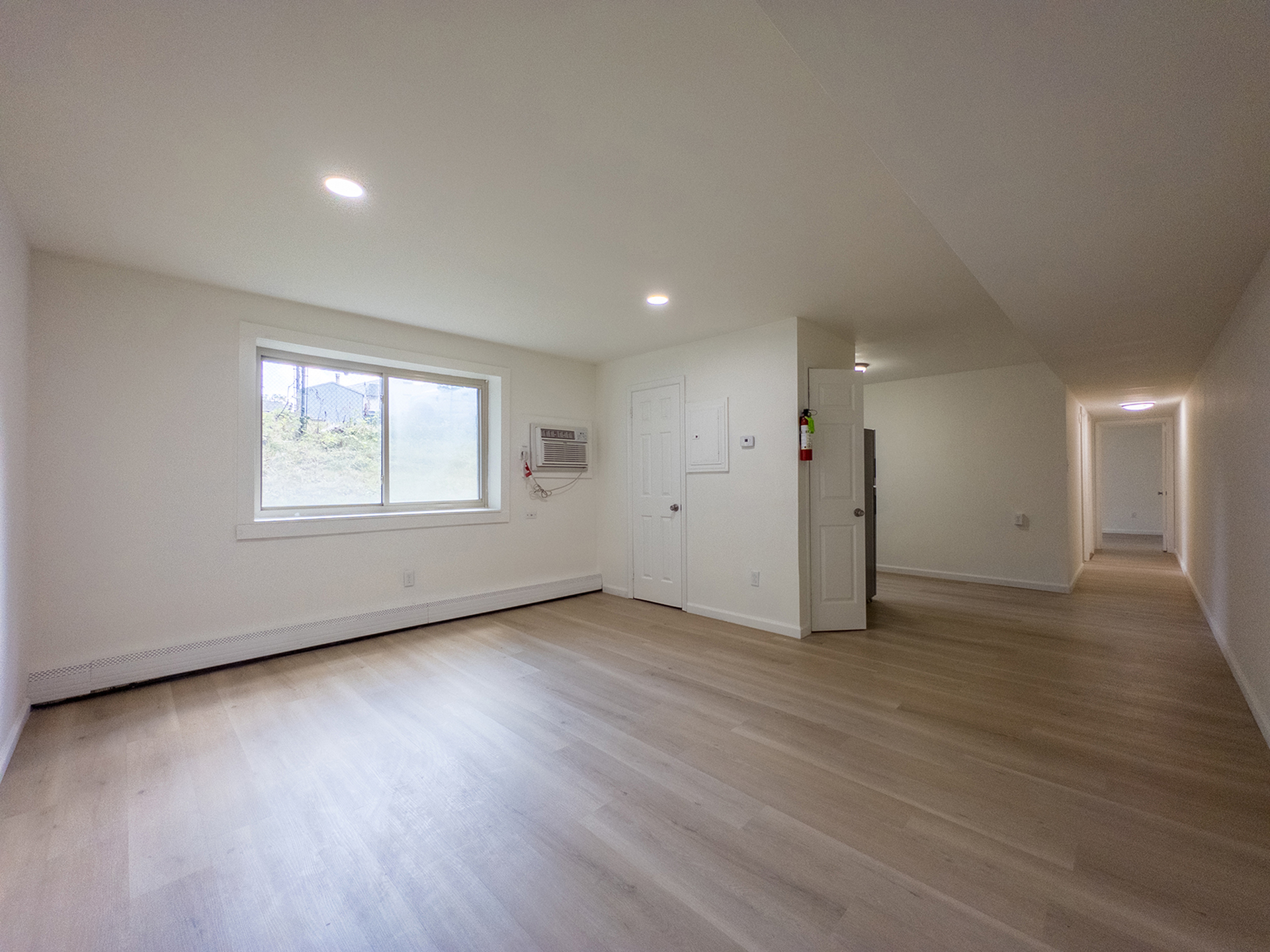 spacious living room with closet and large window, kitchen with pantry, hallway leading to bedrooms