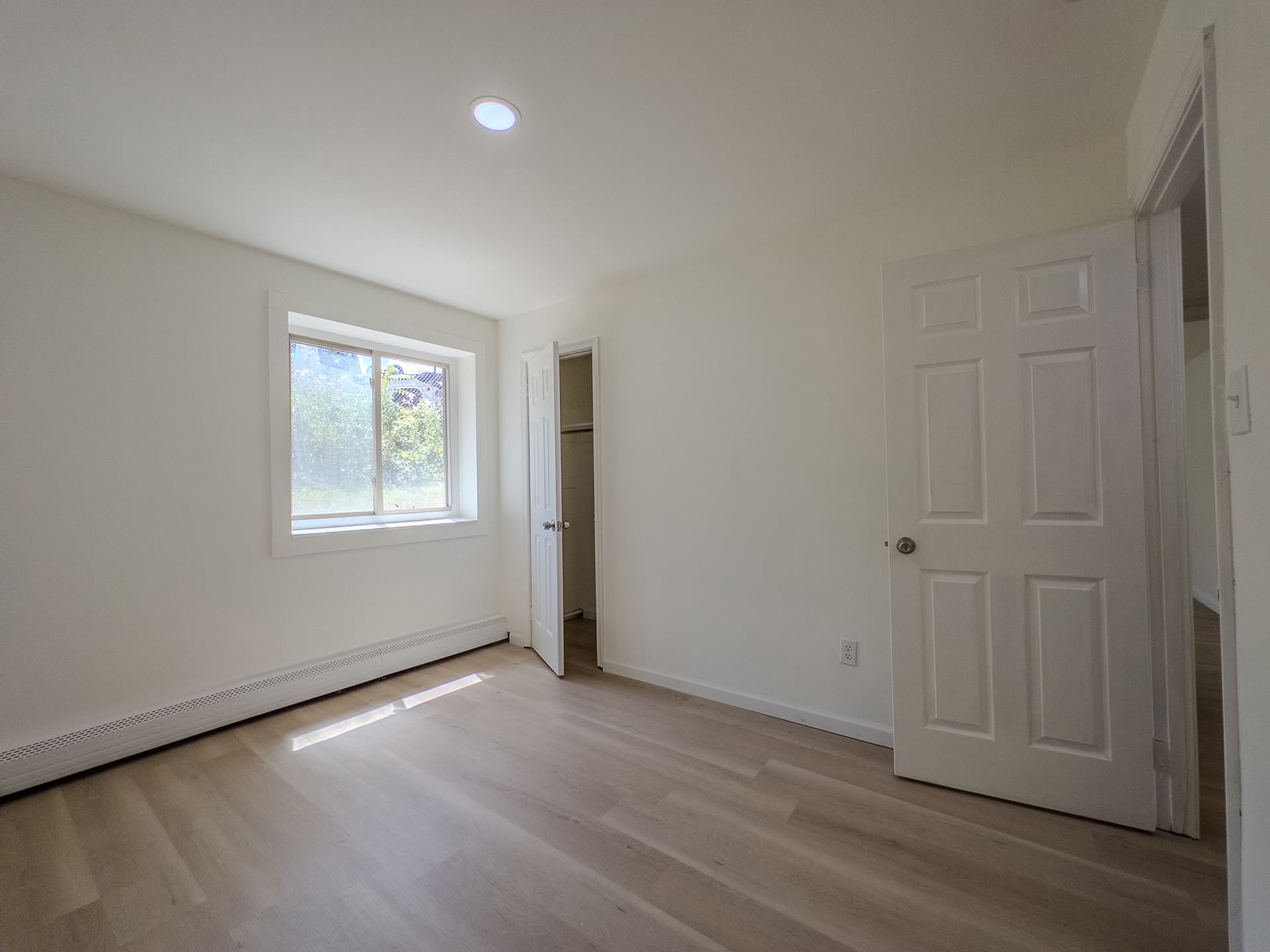 bedroom with window and closet, door leading to hallway