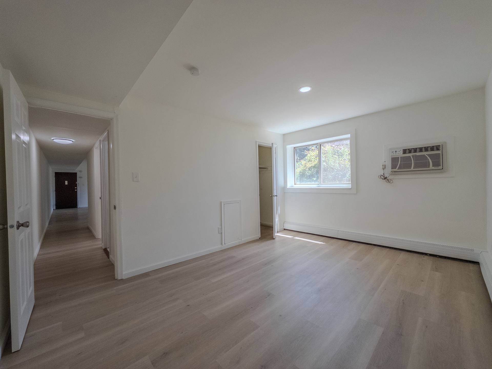 large bedroom with air conditioner, window, closet, door leading to hallway