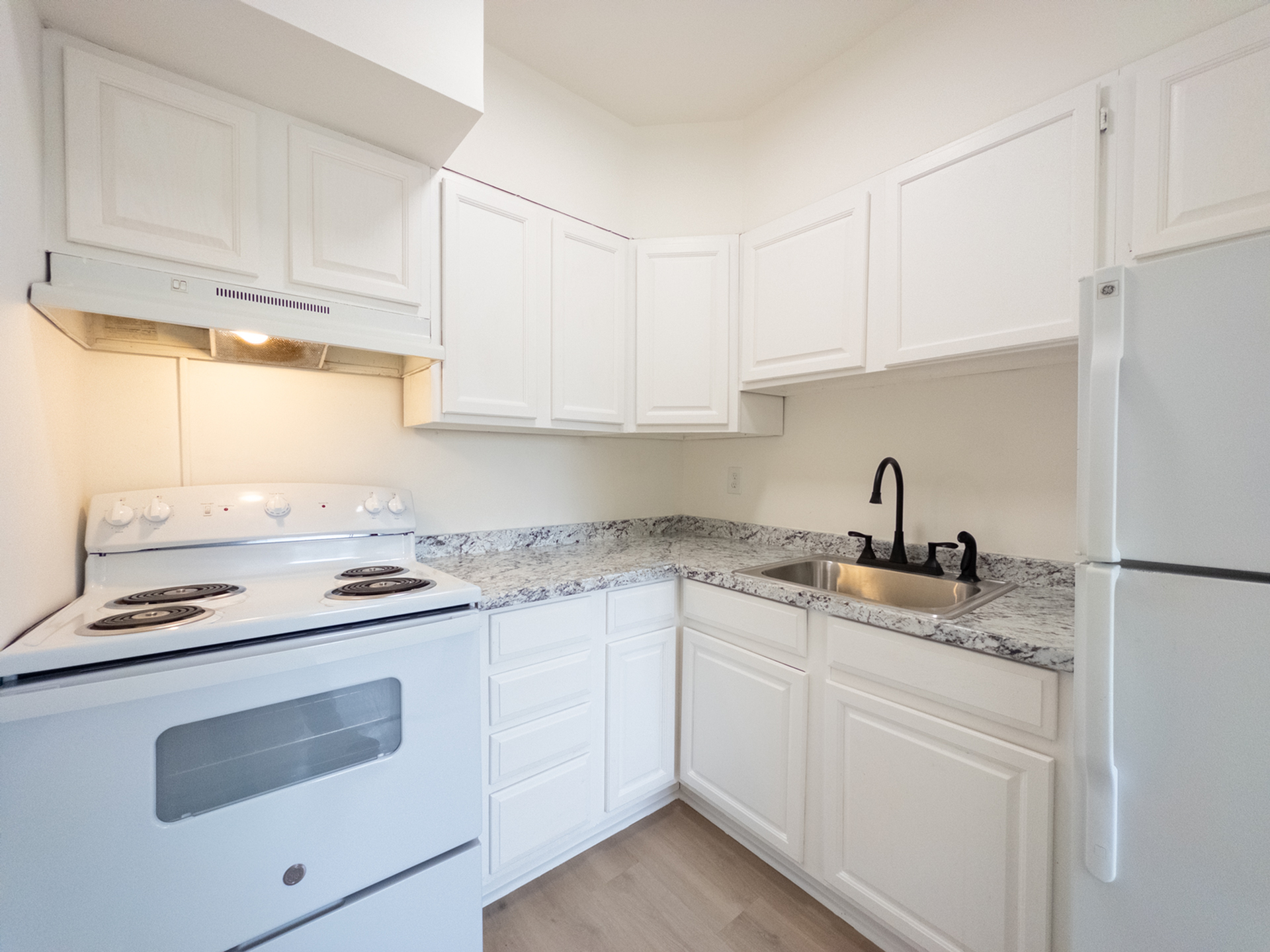renovated apartment kitchen, stone counters, refrigerator, range with hood, updated cabinets and sink fixture
