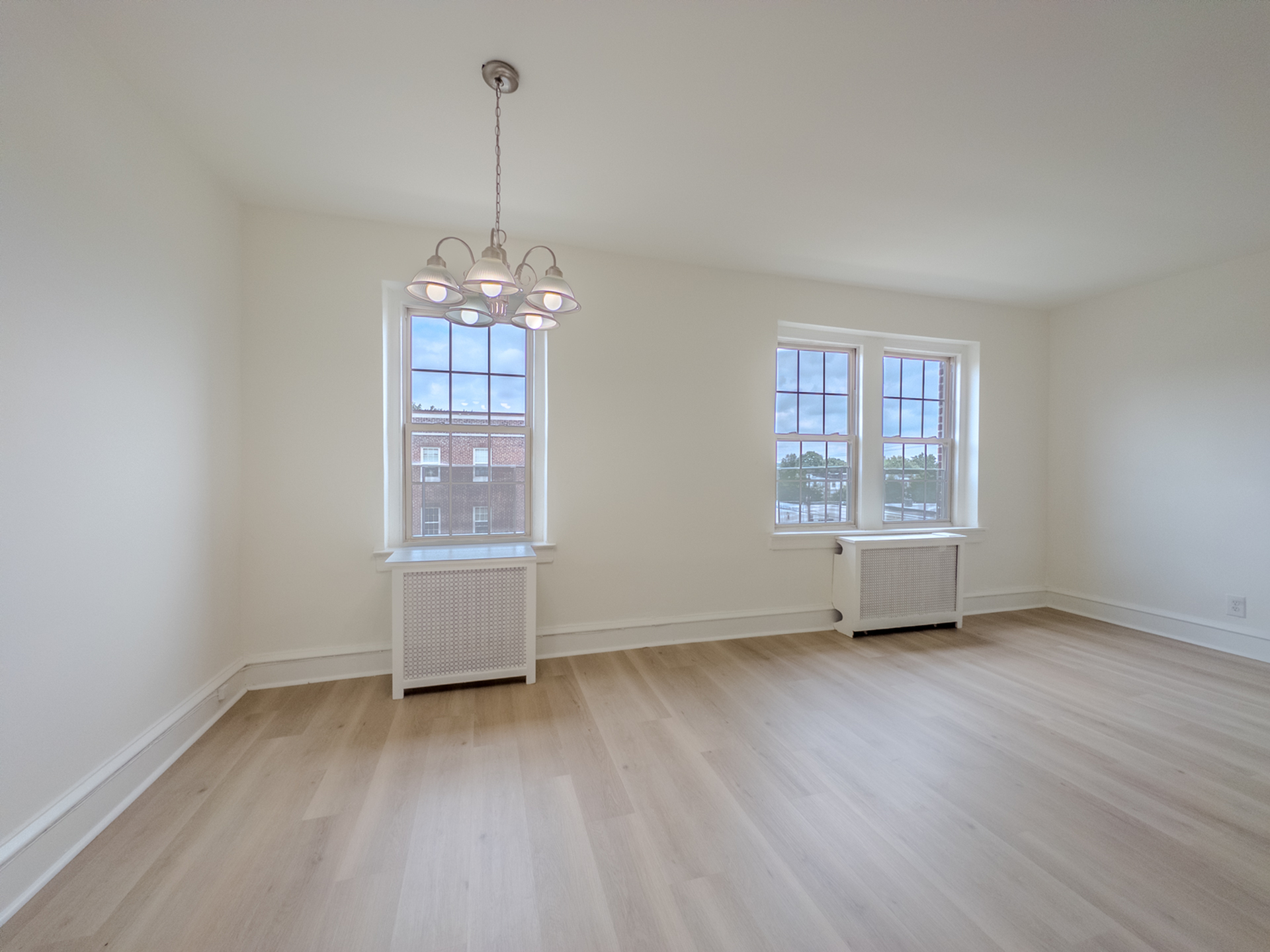 apartment living room with big windows, radiator heat, chandelier, wood floors