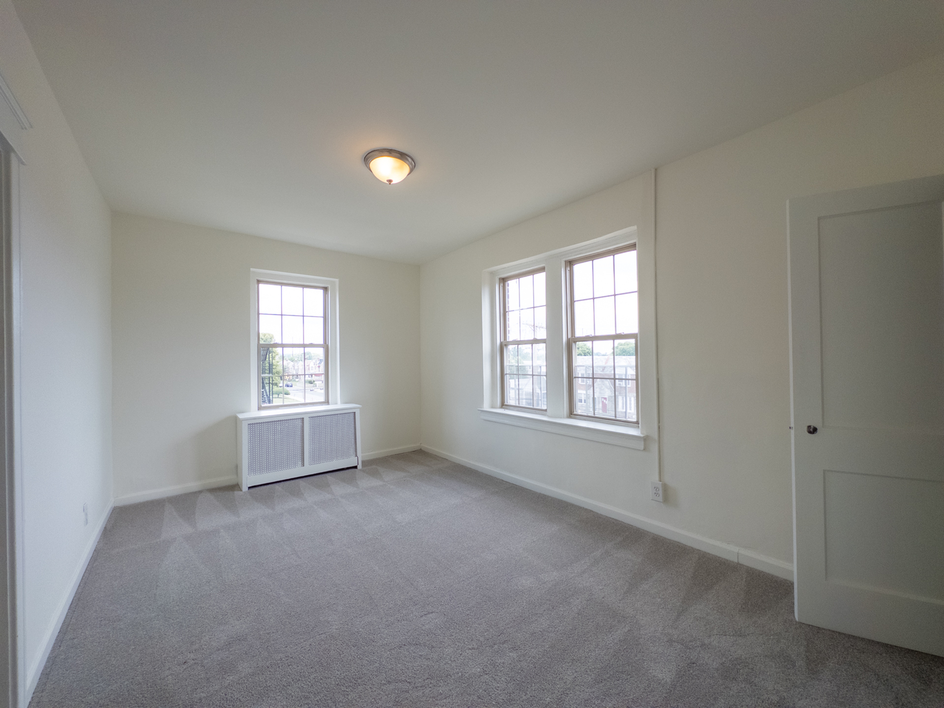 carpeted bedroom with lots of windows, closet, overhead light, radiator heat