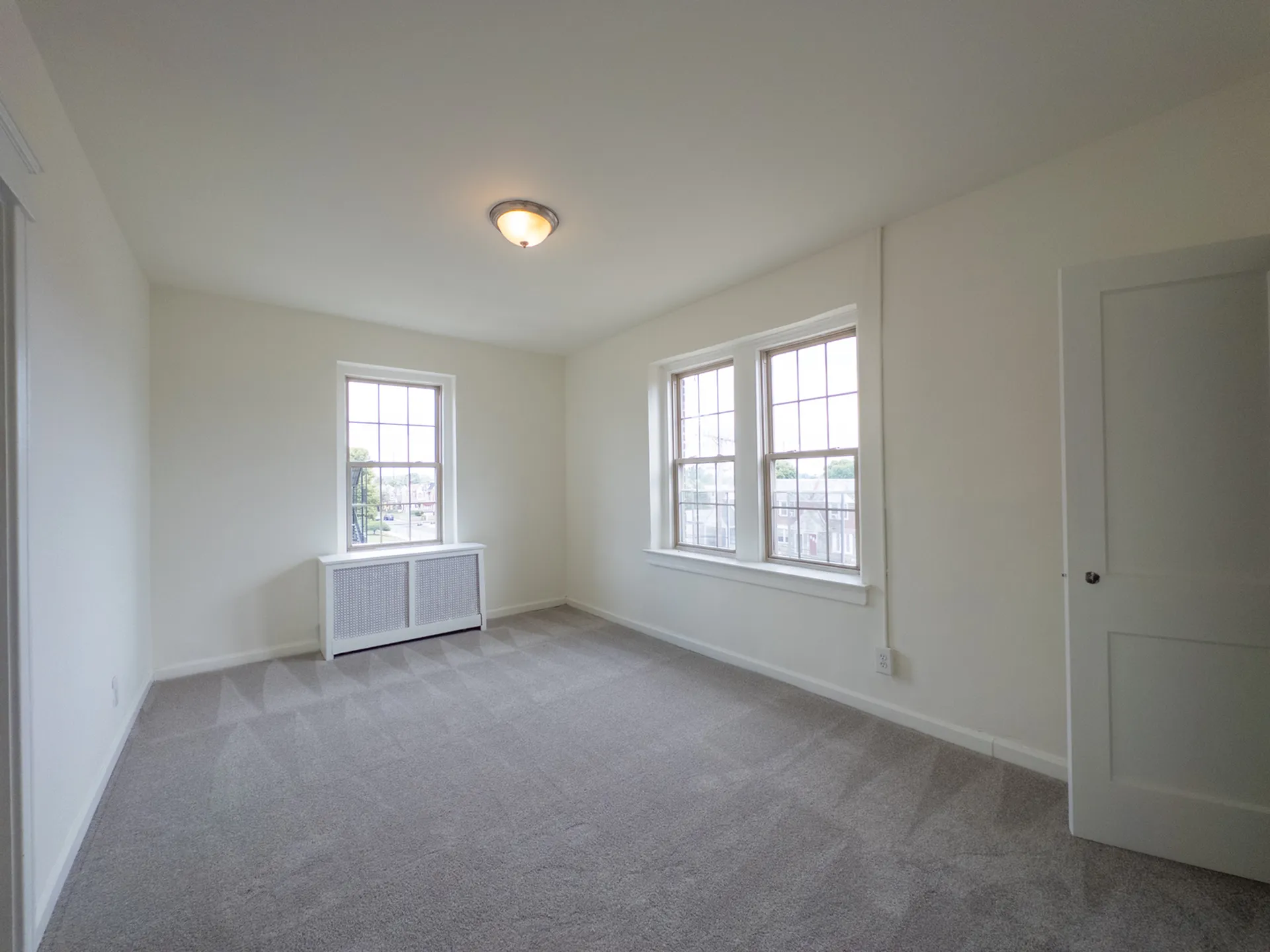 carpeted bedroom with lots of windows, closet, overhead light, radiator heat