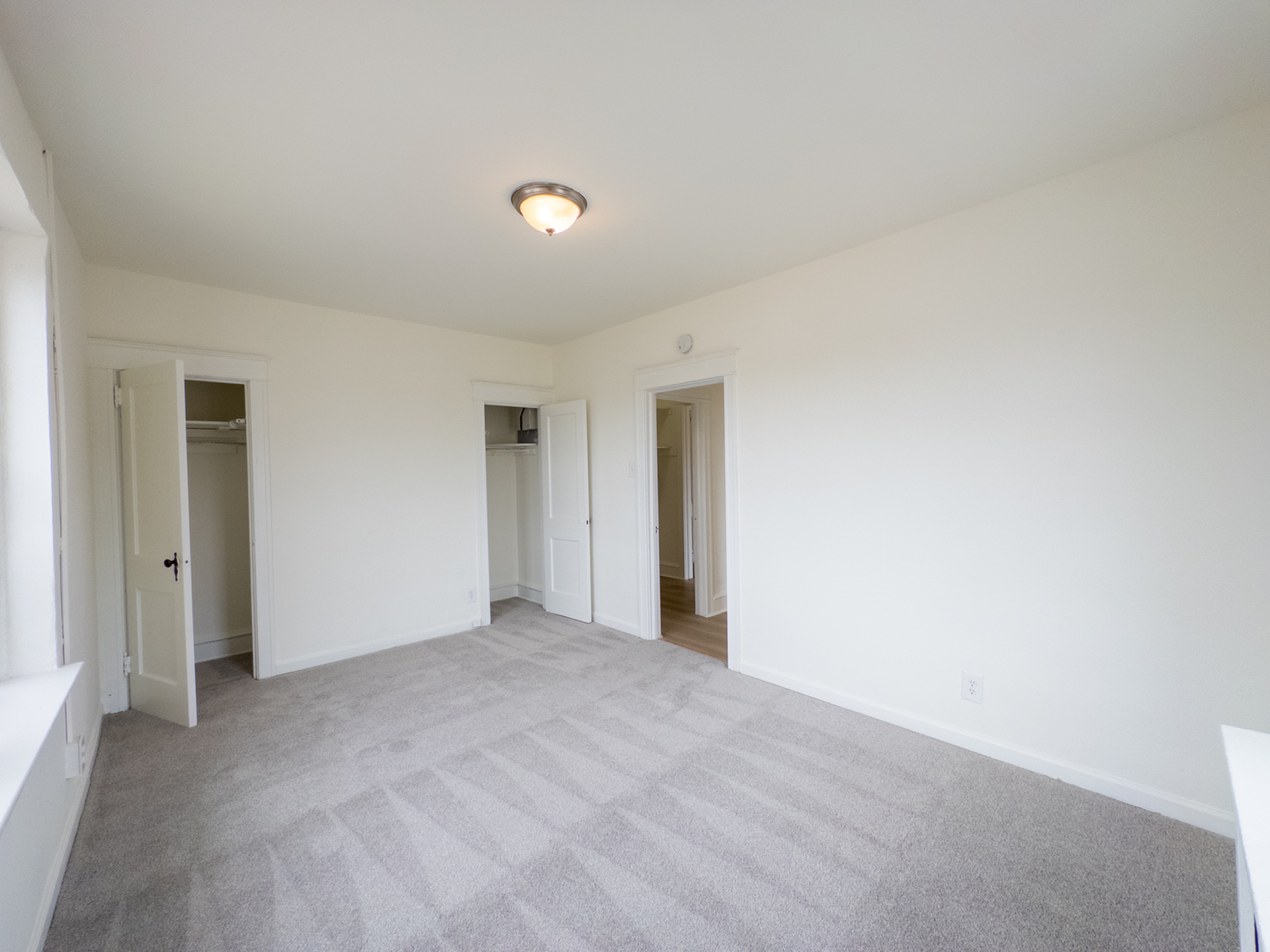 carpeted bedroom with lots of windows, closet, overhead light, radiator heat, door leading to hall