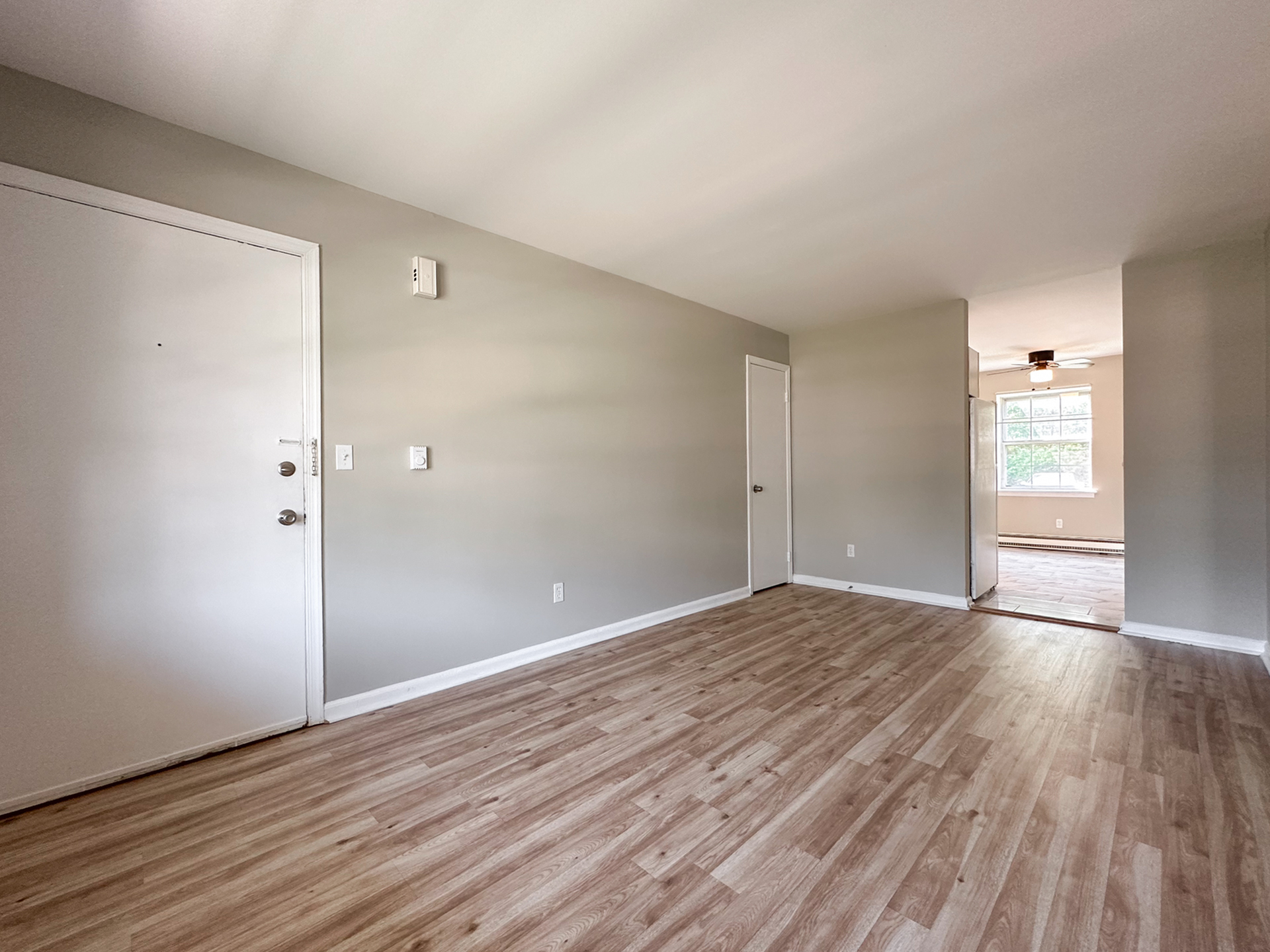 renovated living room, wood panel floor, closet, doorway leading to kitchen with ceiling fan