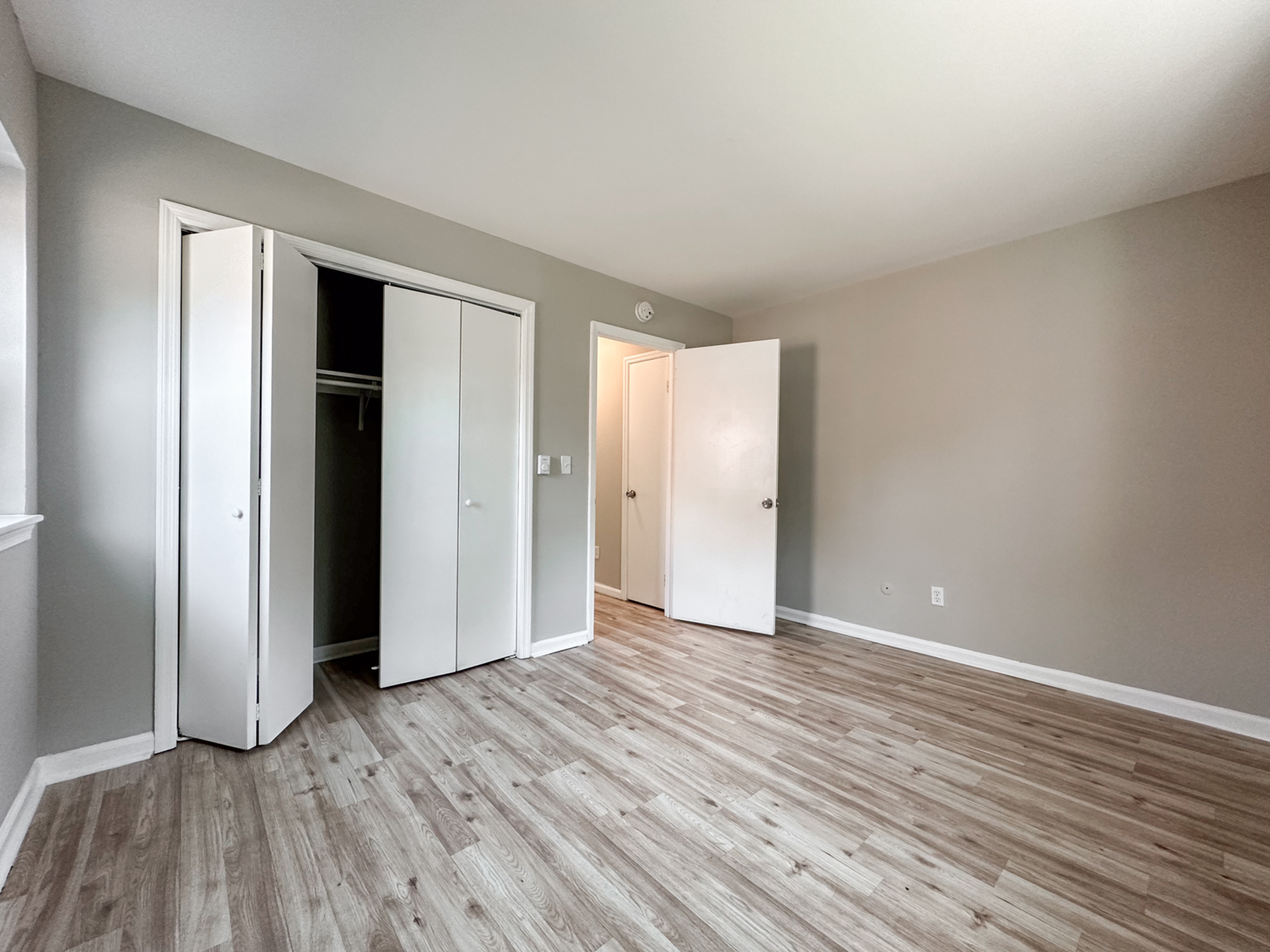 bedroom with wood floor, closet, door leading to hallway