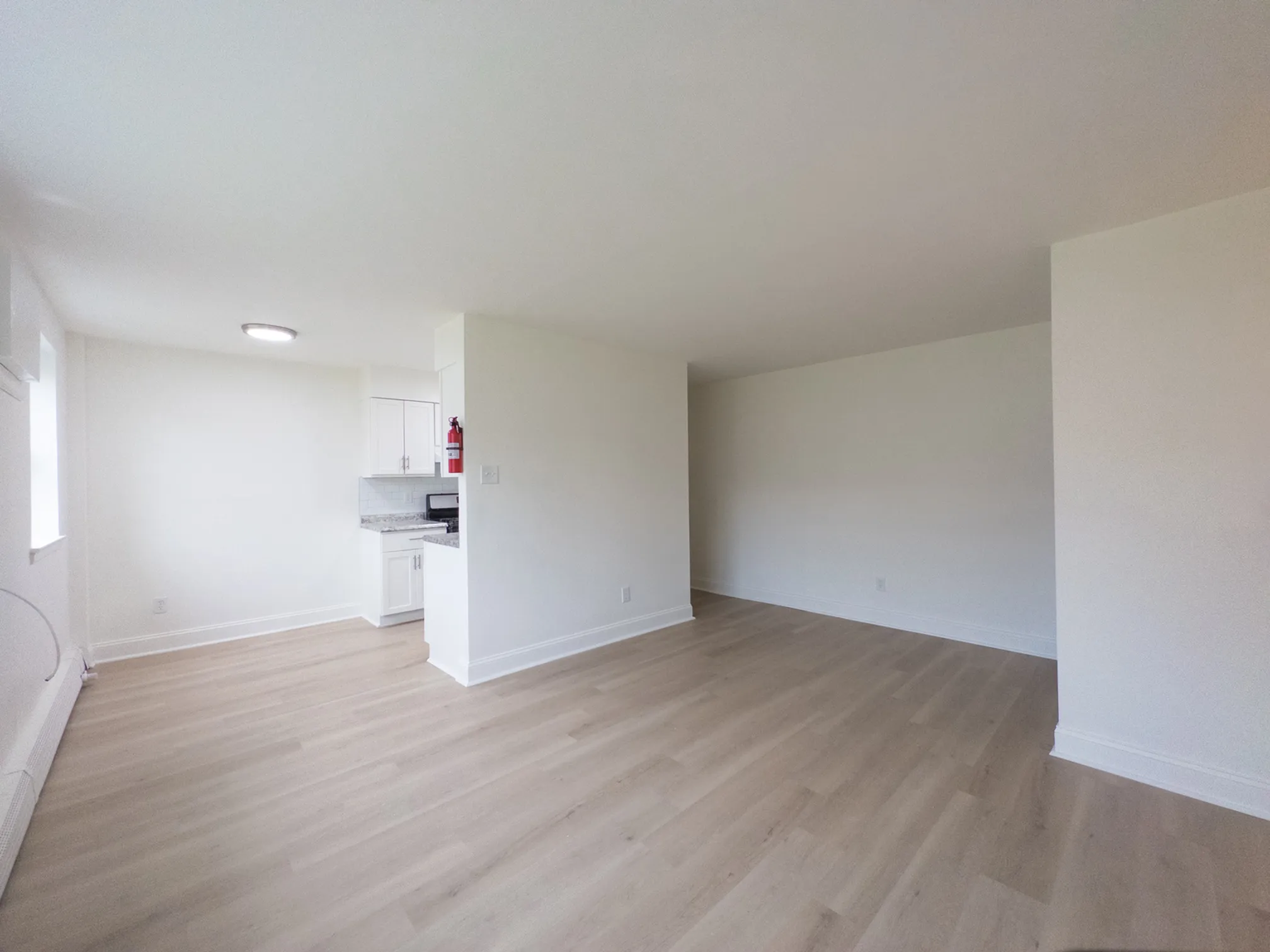 spacious living room with wood floor, leading to open kitchen