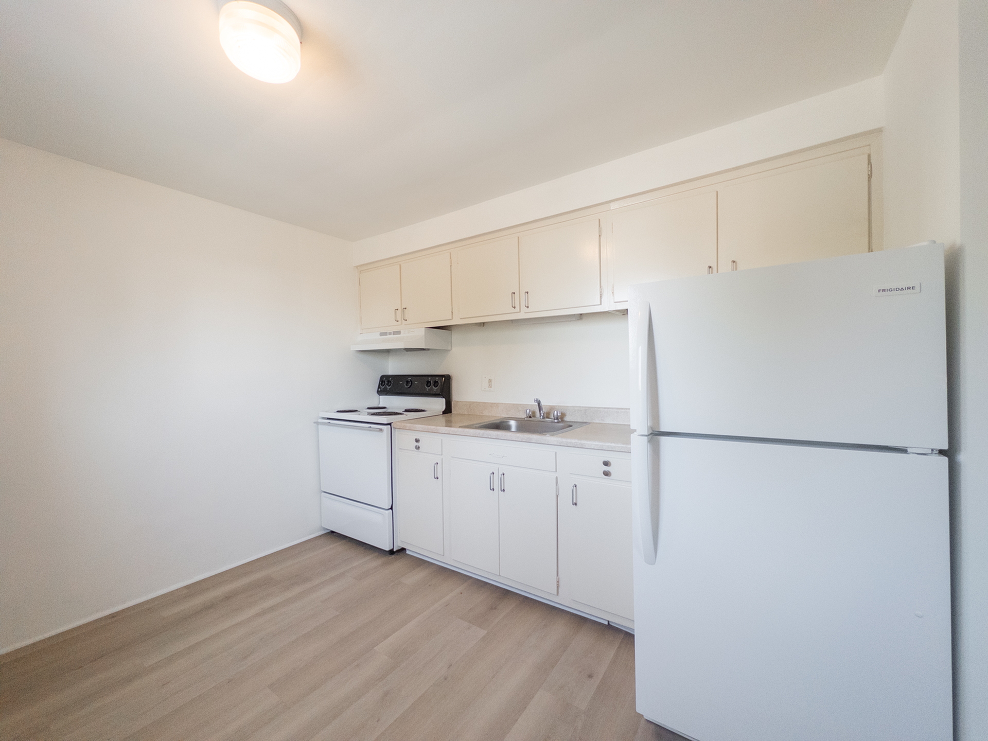 kitchen with refrigerator and range included, cabinets and sink with stone counter