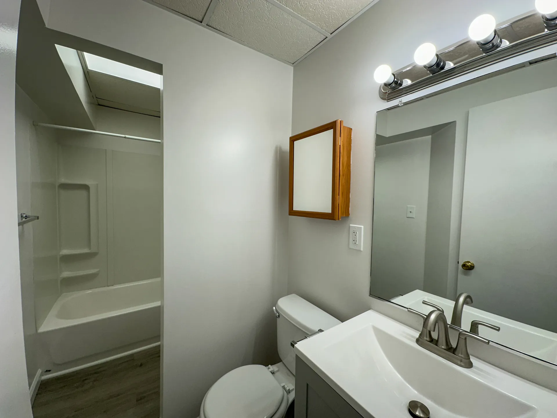 Modern bathroom with sleek vanity, bright lights, and a spacious bathtub.