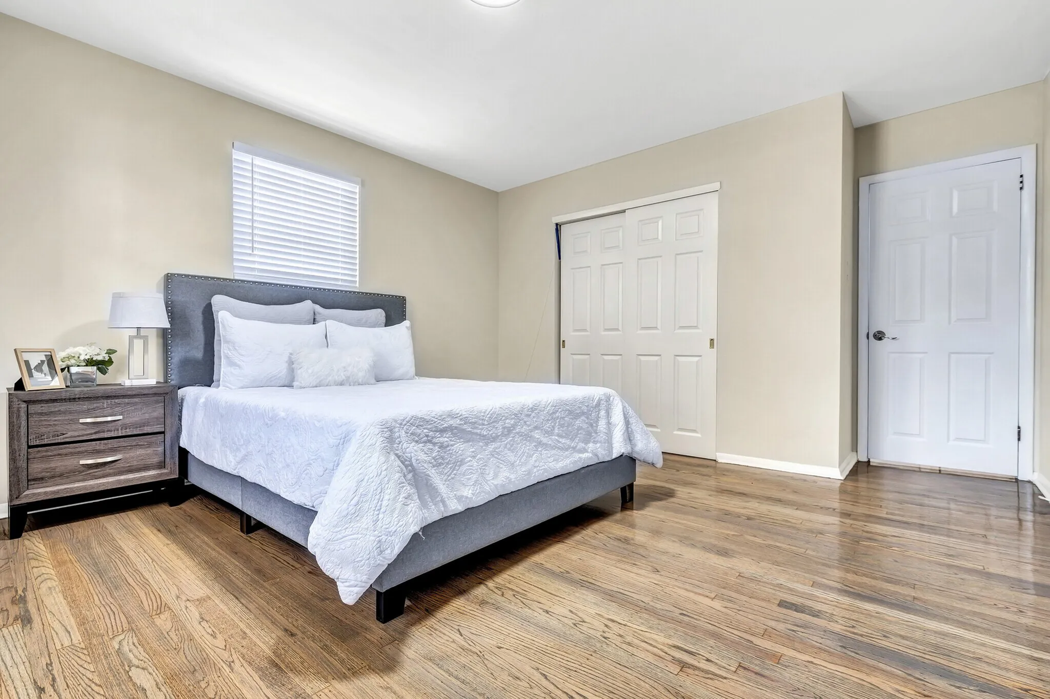 Inviting bedroom with a plush bed, elegant wooden floors, and abundant natural light, ideal for relaxation.