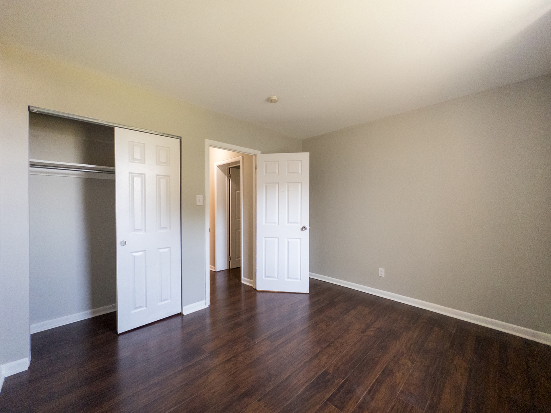 Bright and spacious bedroom with elegant hardwood floors and ample closet space, perfect for comfortable living.