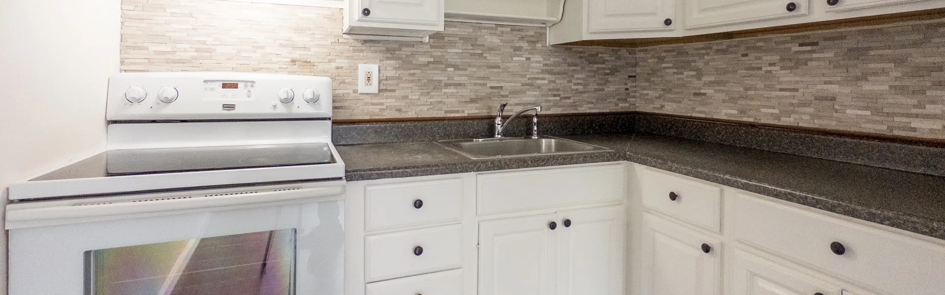 kitchen with oven/stove and range hood with fan and light, tile backsplash, lots of cabinets, stone counter tops