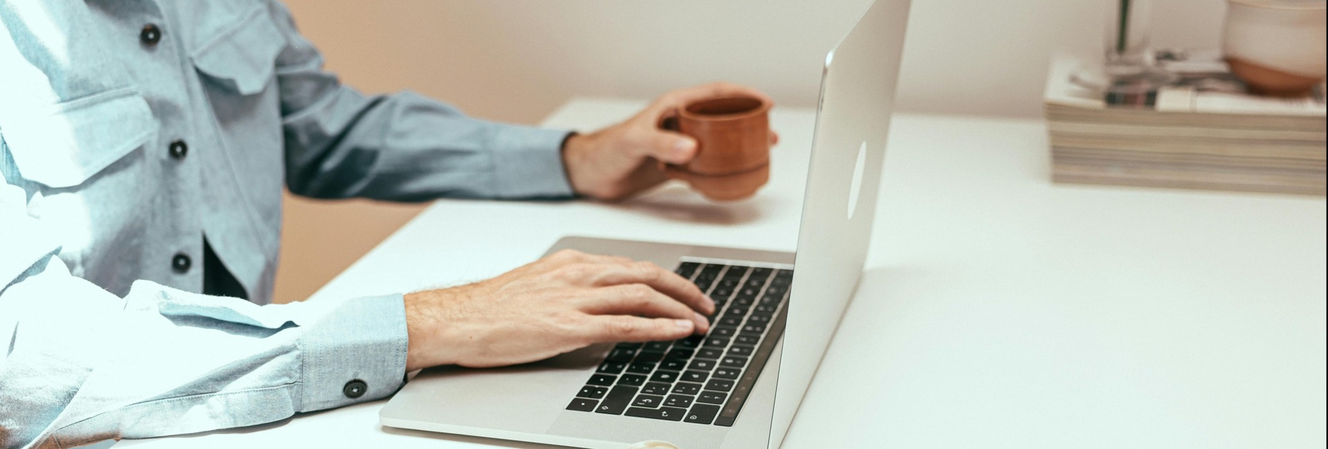 person holding coffee and using their laptop computer on a table