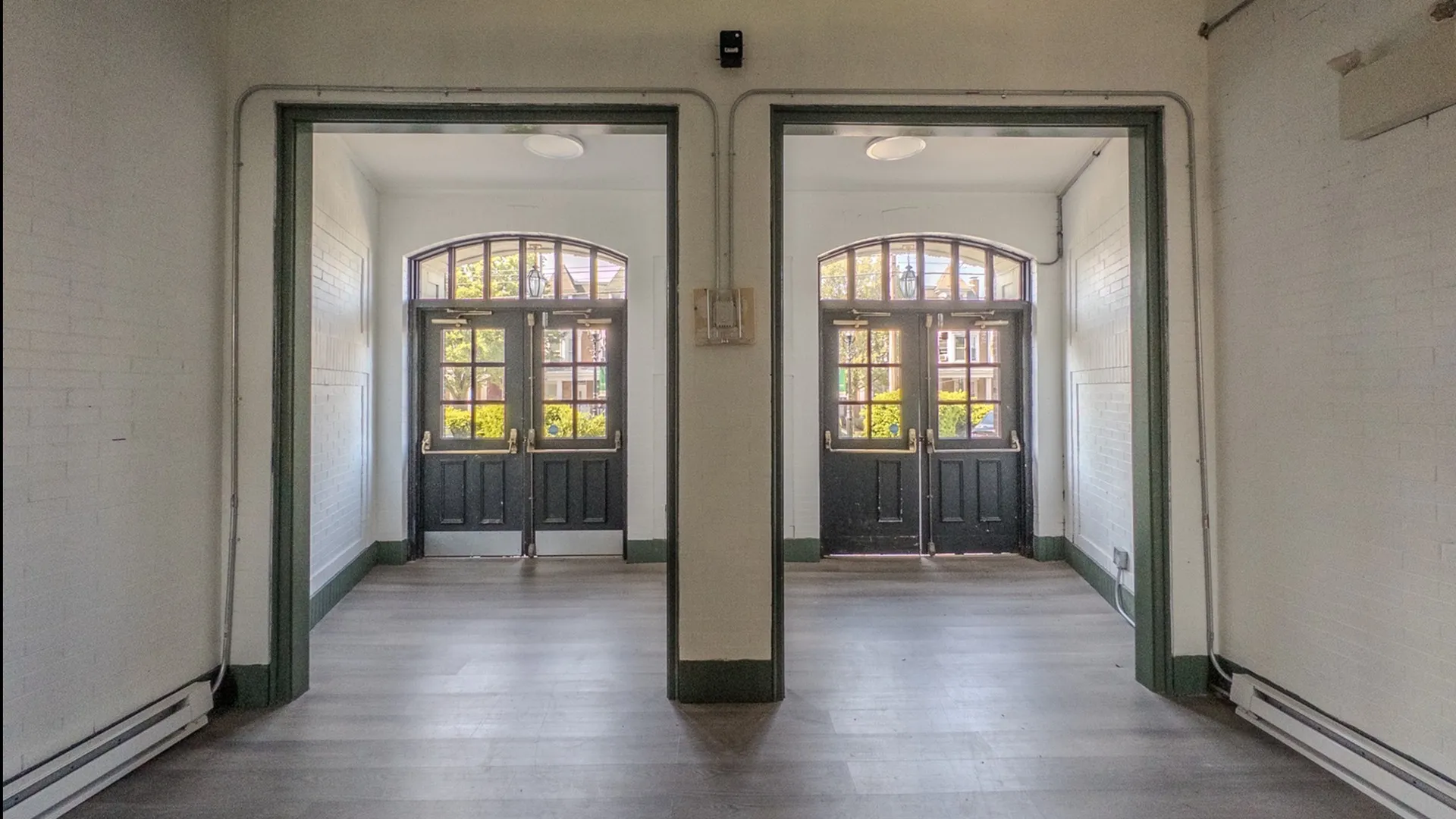large entrance to building, view from inside, two sets of green double doors