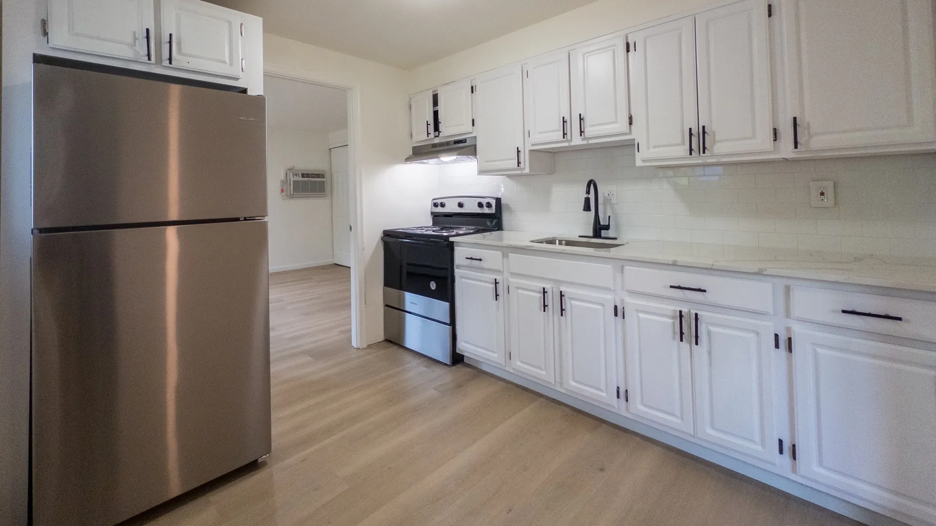 renovated kitchen with white cabinets, stone countertop, and new stainless steel appliances