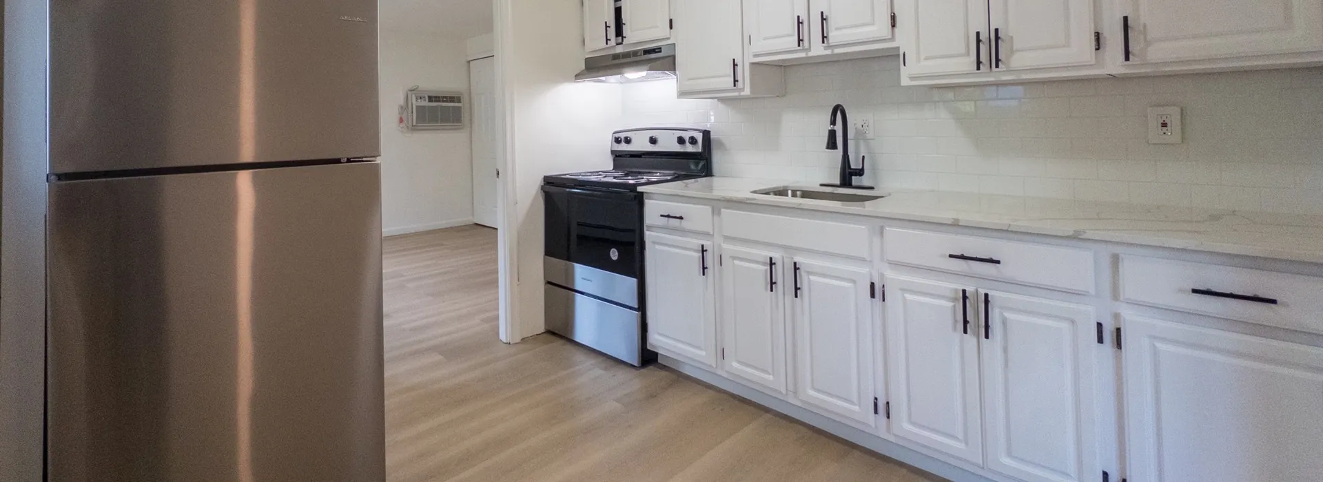 renovated kitchen with white cabinets, stone countertop, and new stainless steel appliances