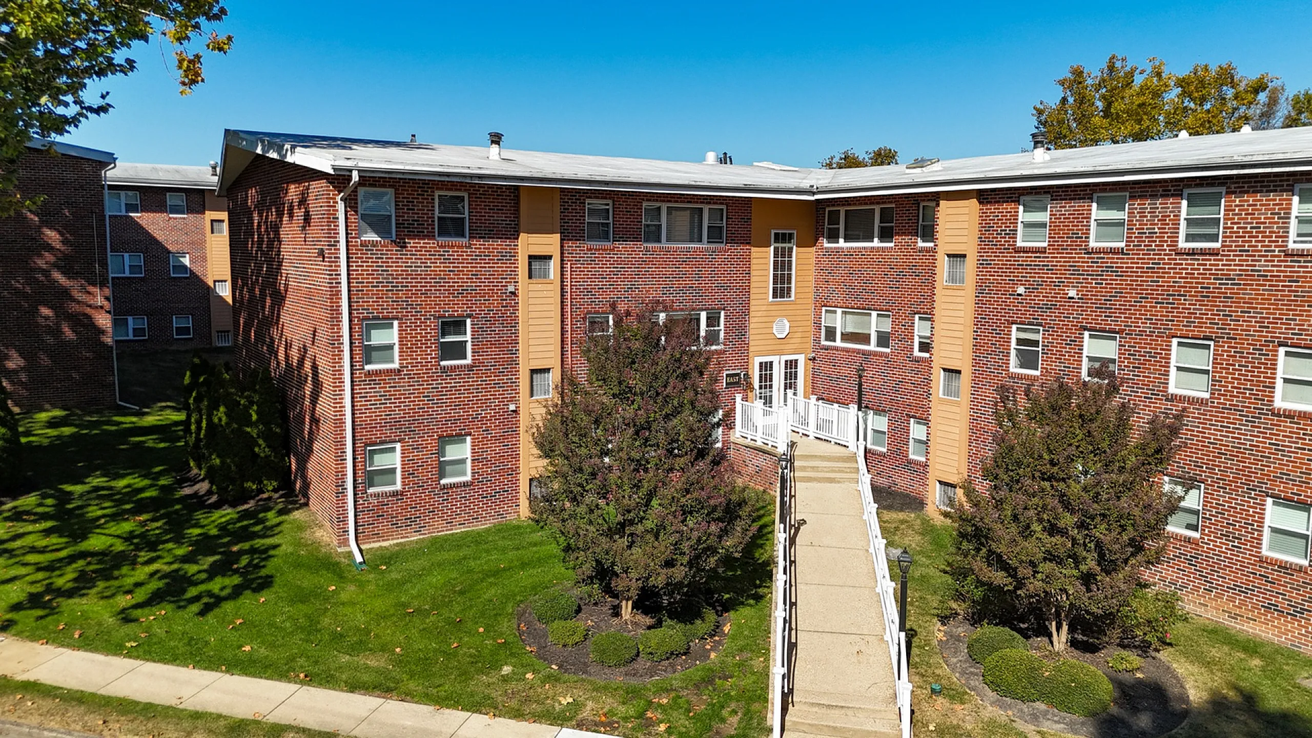exterior view of springfield valley apartments, springfield pa, brick building with manicured landscaping, walkway to entrance
