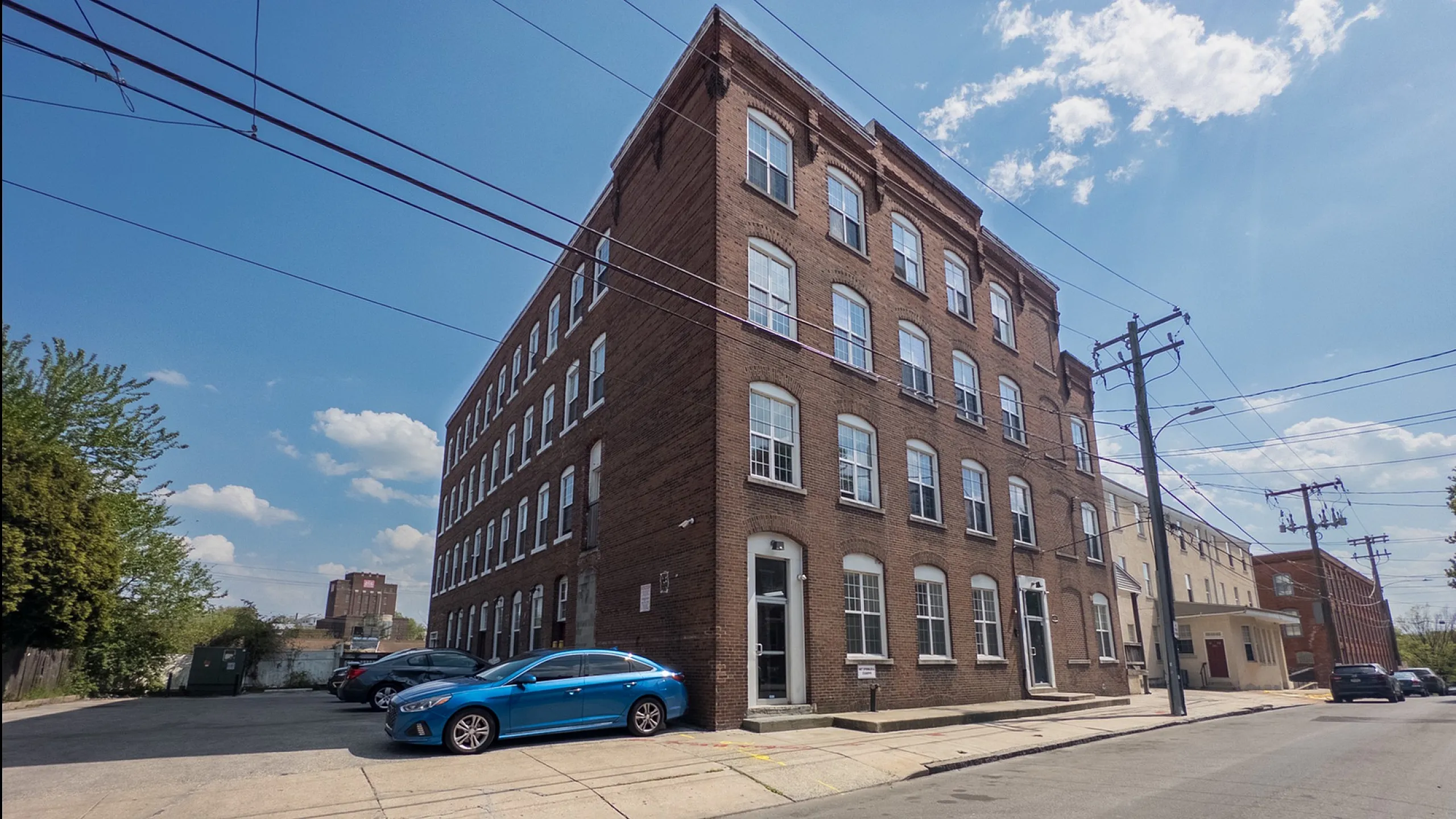 Charming brick building with modern windows on a sunny street, offering convenient street parking and an inviting urban atmosphere.