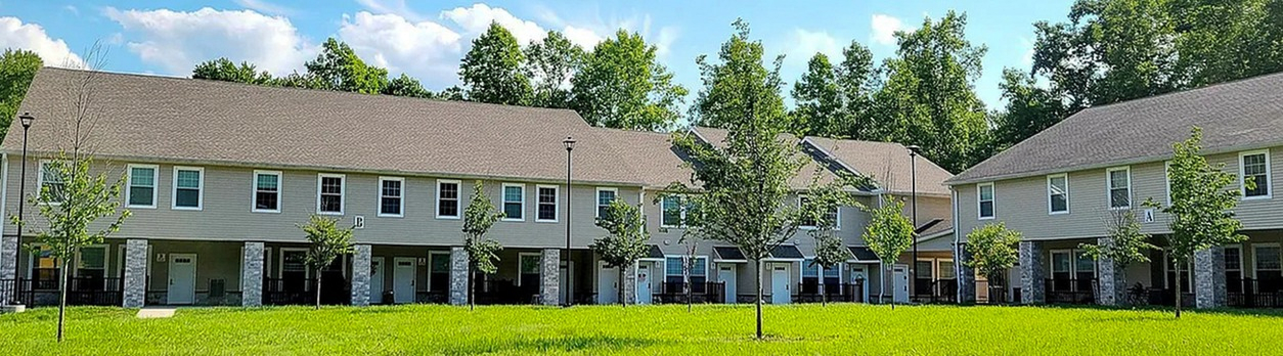 Charming townhouse complex with beautiful green lawns and mature trees, perfect for serene living.