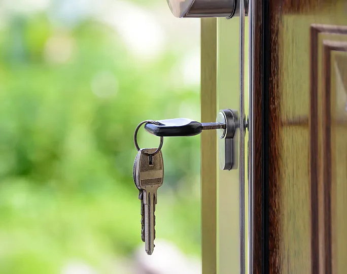 Inviting entryway with a shiny new key in the door, overlooking a lush green garden.